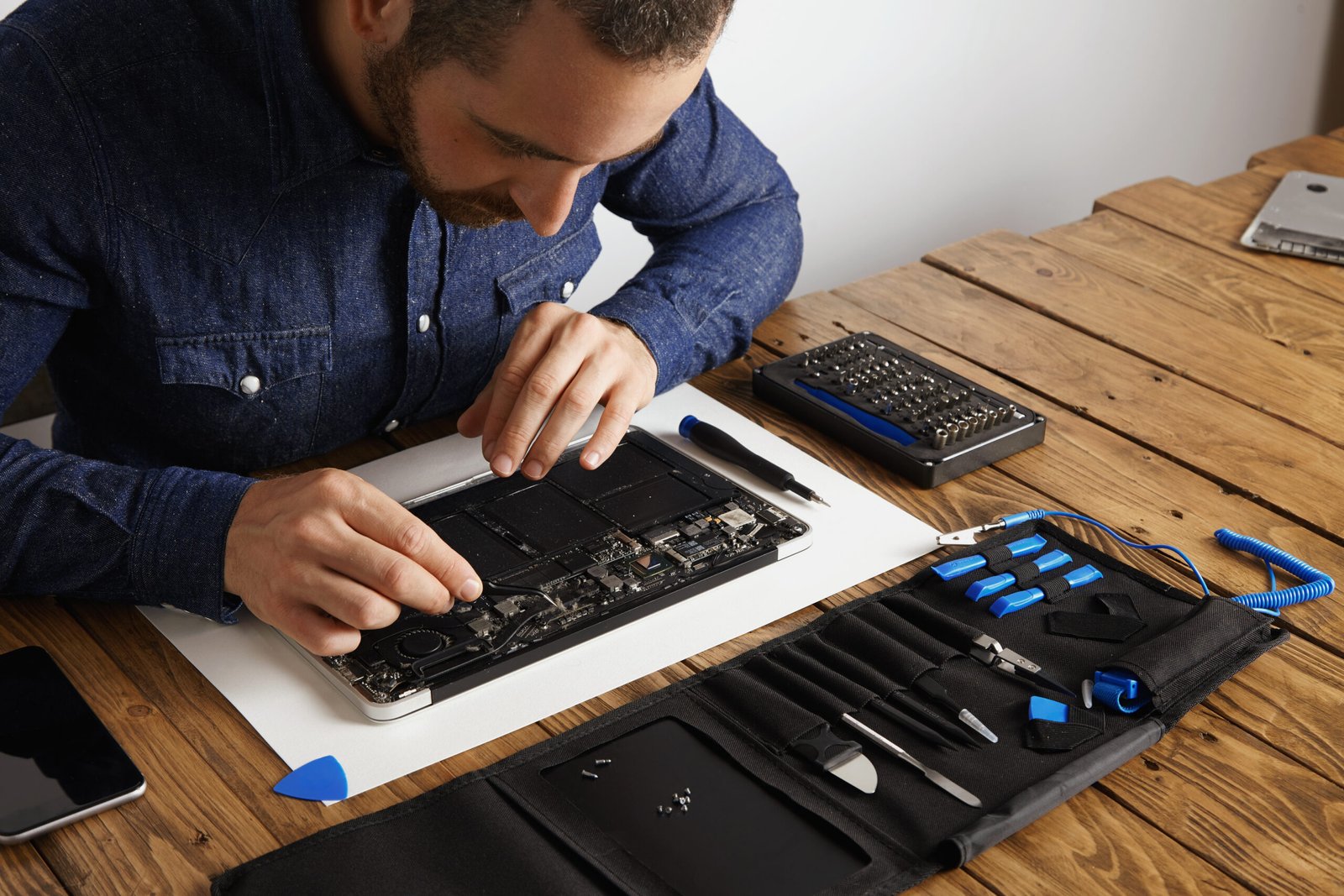 Master uses angled esd tweezers to remove dust from electronic boards of broken slim computer laptop to fix it and make to work again